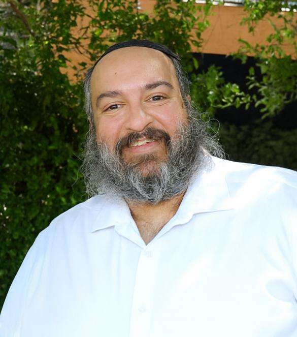 Man smiling outdoors with trees in background.